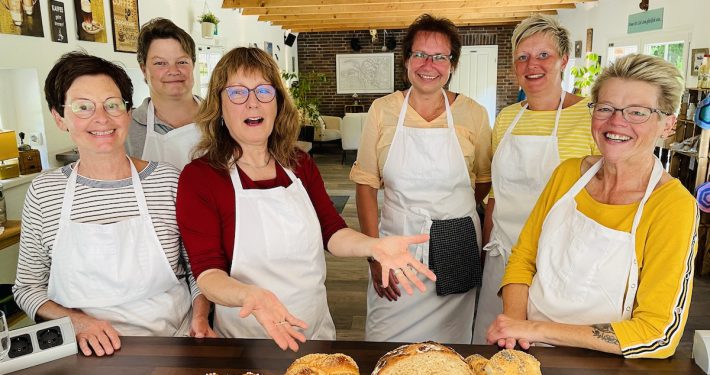 6 Frauen präsentieren stolz Brot und Brötchen in der Backstube