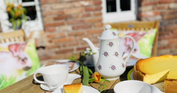 gedeckter Tisch draussen im Sommer mit Tee und Käsekuchen